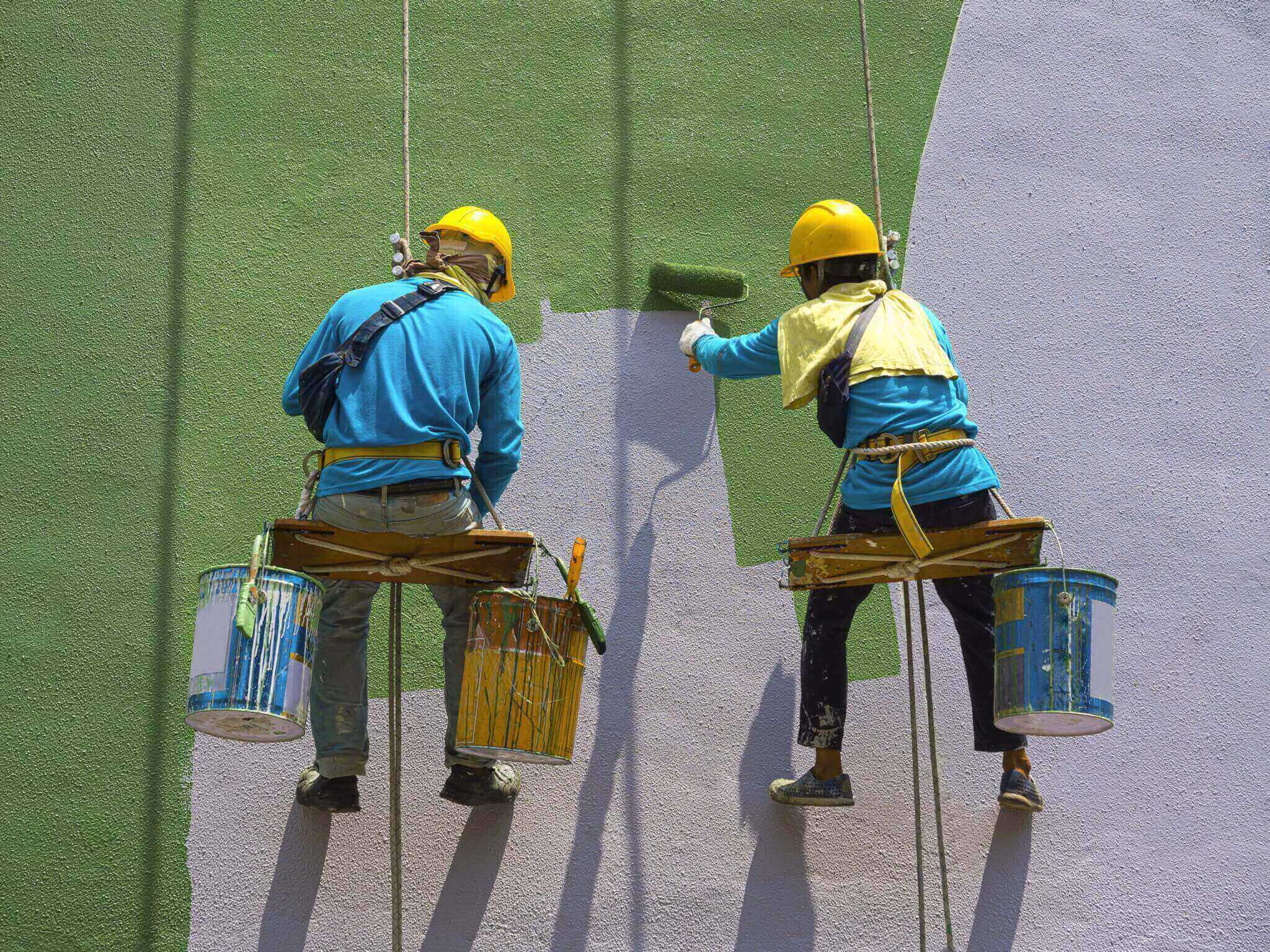 робітники фарбують фасад