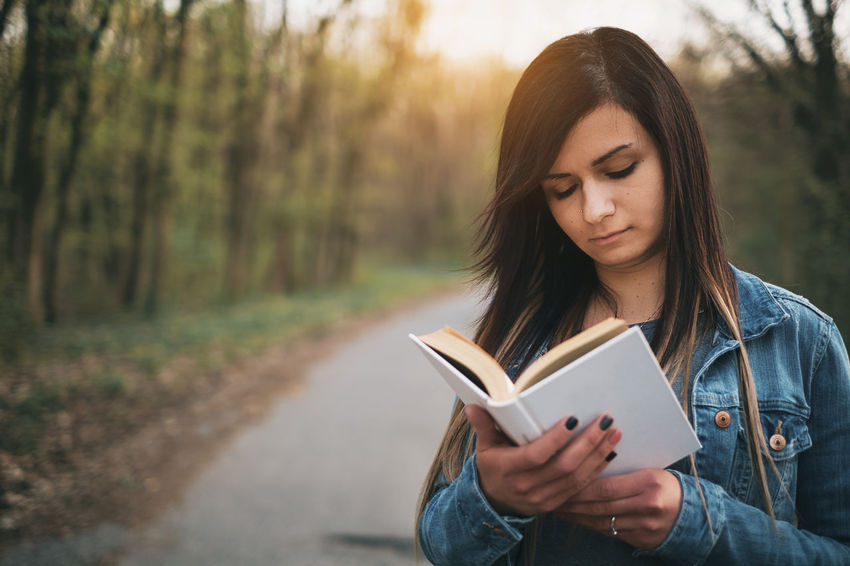 На фото молодая девушка увлечена чтением книги