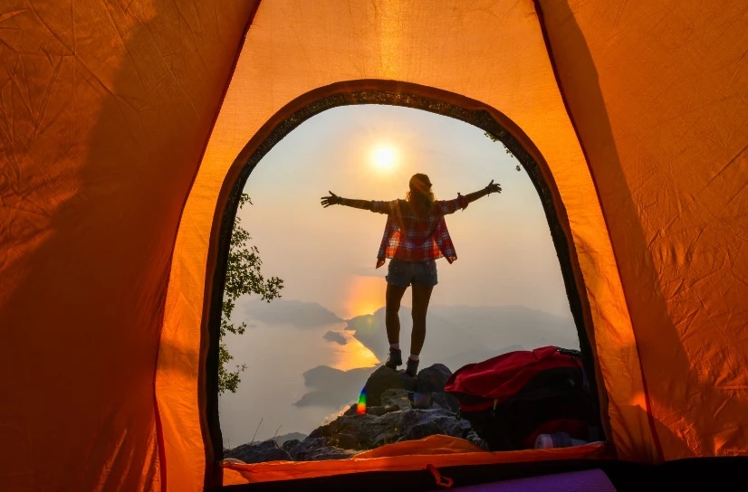 палатка, вид из палатки на улицу где стоит девушка радуется восходу солнца