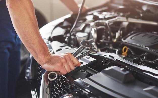 Free photo muscular car service worker repairing vehicle.